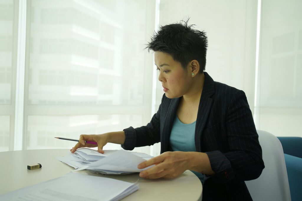Businesswoman reviewing documents at a round table in a bright office space.